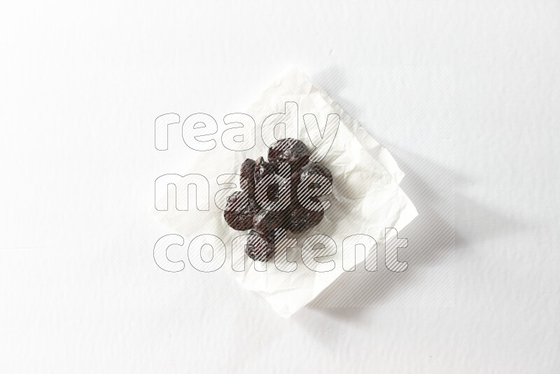 Dried plums on a crumpled piece of paper on a white background in different angles