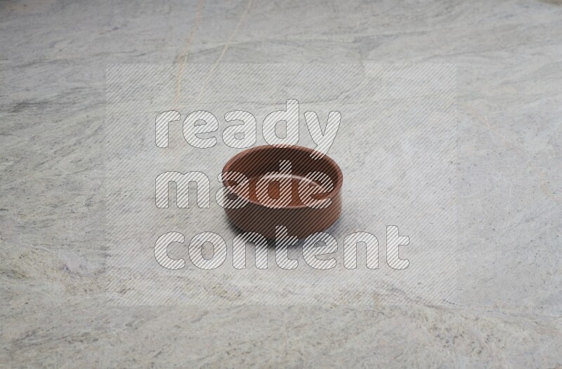 A brown pottery bowl on grey marble background