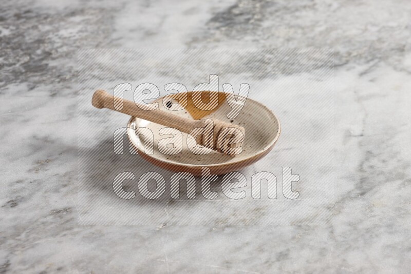 Multicolored pottery plate with wooden honey dipper in it on grey marble background
