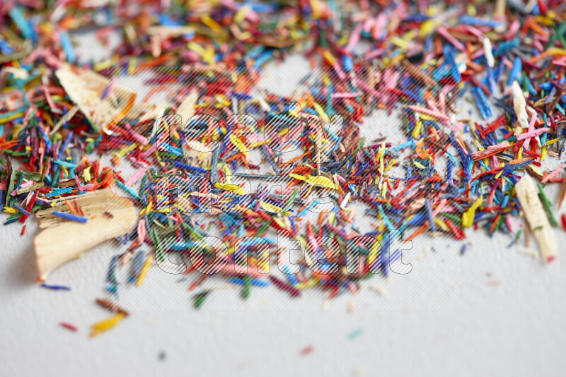 This image showcases a vibrant multicolored pencil shavings scattered on grey background