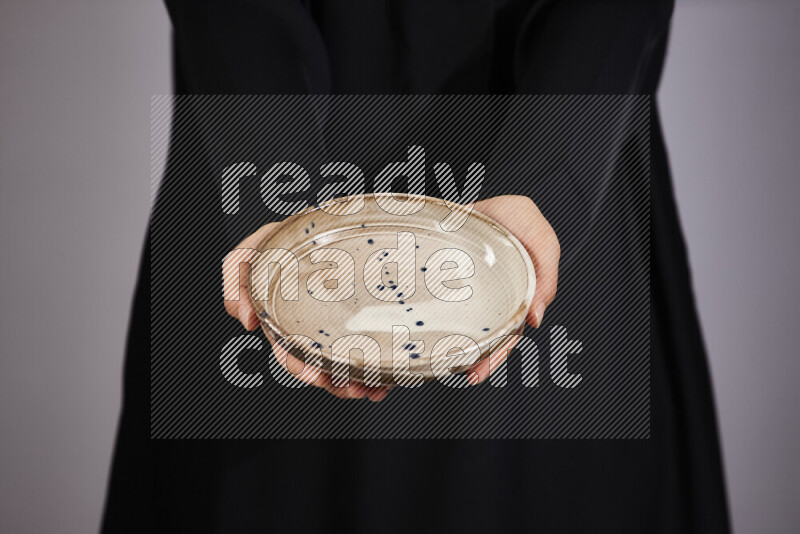 A woman in black abaya holding different pottery essentials in different positions