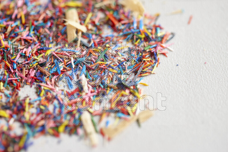 This image showcases a vibrant multicolored pencil shavings scattered on grey background