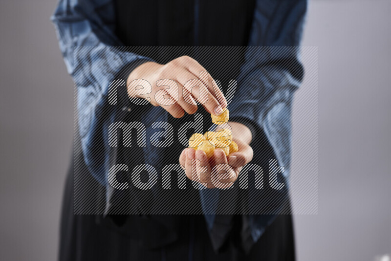 Woman in abaya holding different kinds of snacks in different positions