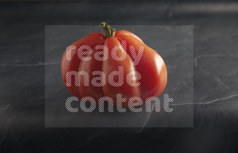 45 degree single heirloom tomato on a textured black slate background