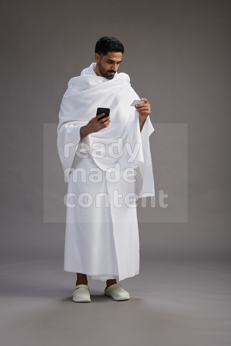 A man wearing Ehram Standing holding ATM card on gray background