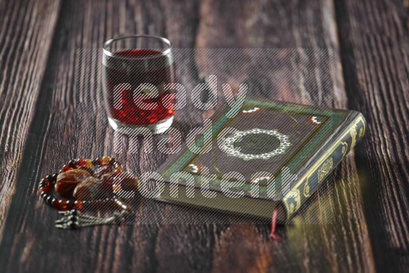 Quran with dates, prayer beads and different drinks all placed on wooden background