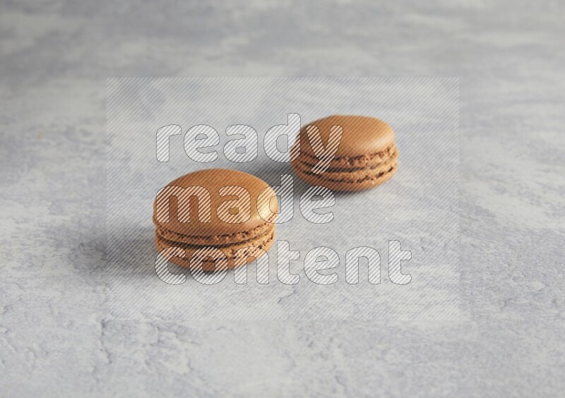 45º Shot of two Brown Coffee macarons  on white  marble background