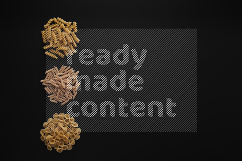 Different pasta types in 3 bunches on black background