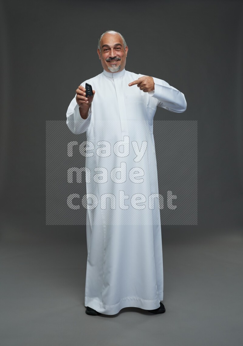 Saudi man without shomag Standing holding car key on gray background