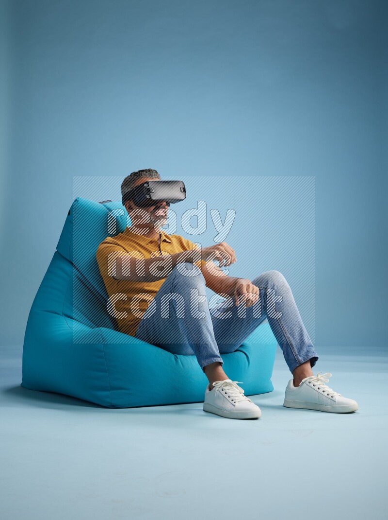 A man sitting on a blue beanbag and gaming with VR