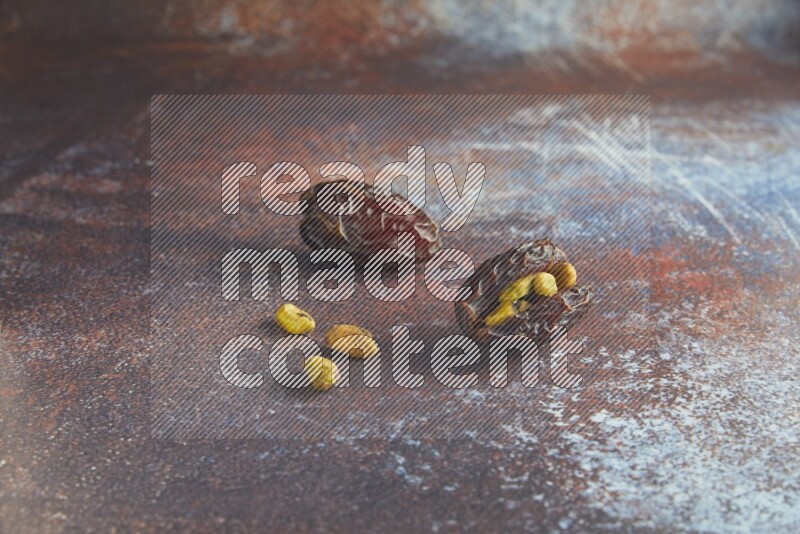 two pistachio stuffed madjoul dates on a rustic reddish background