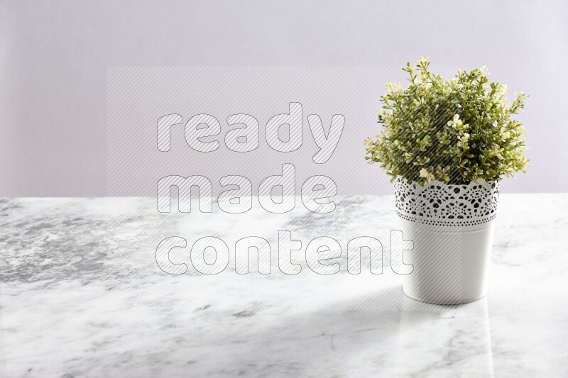 Artificial plant in white decorative pot on grey marble background