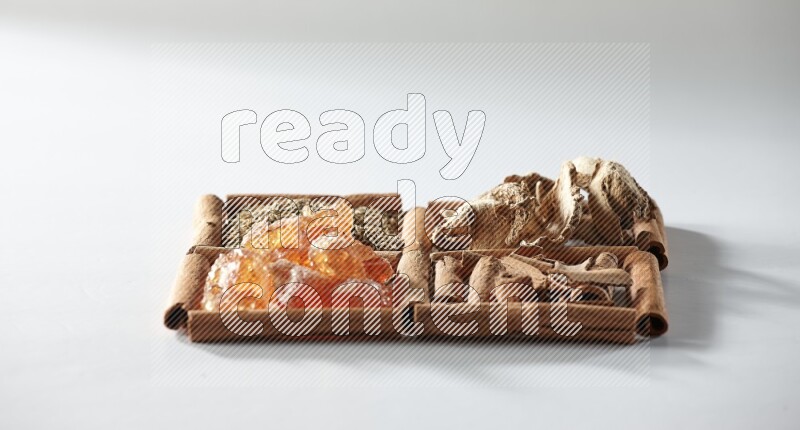 4 مربعات من أعواد القرفة ممتلئة بالكمون والقرفة والزنجبيل المجفف والصمغ العربي على أرضية بيضاء