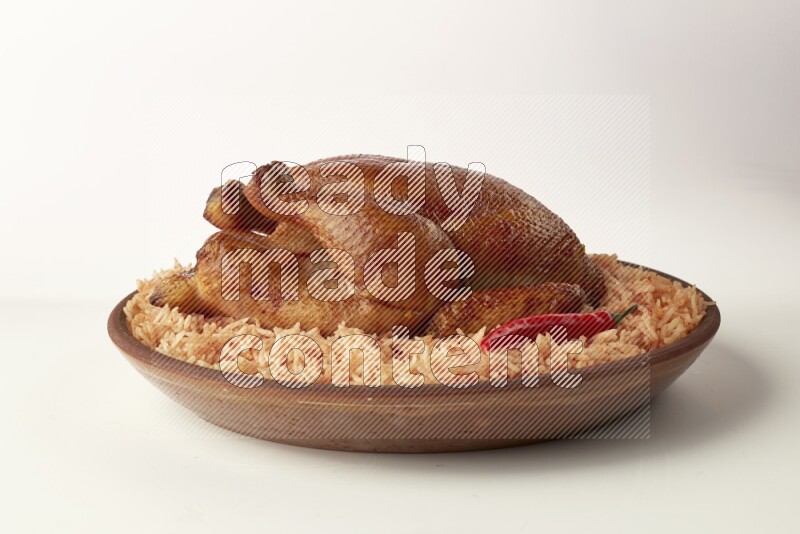 red basmati Rice with whole roasted chicken on a pottery plate direct on white background