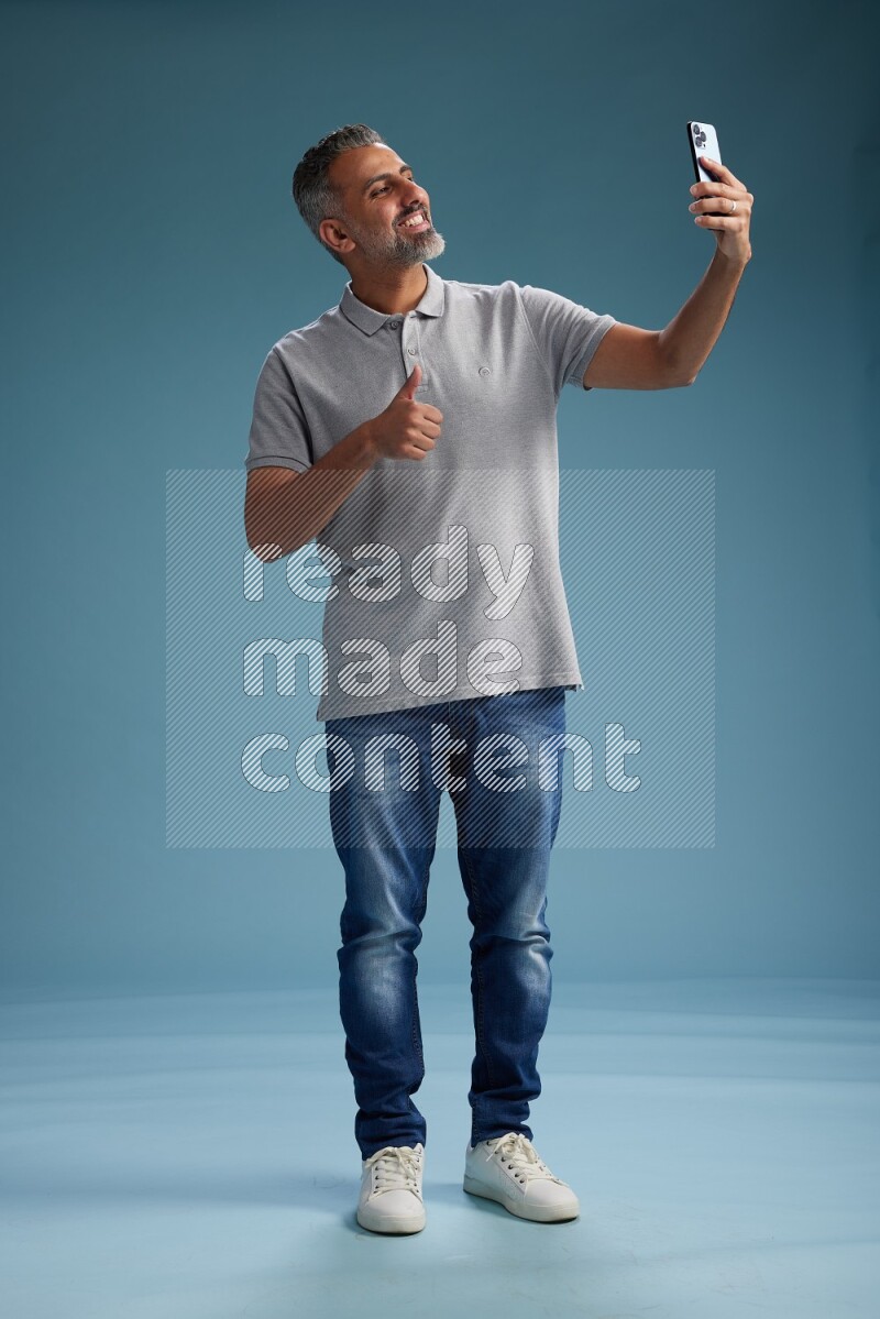 Man Standing taking selfie on blue background