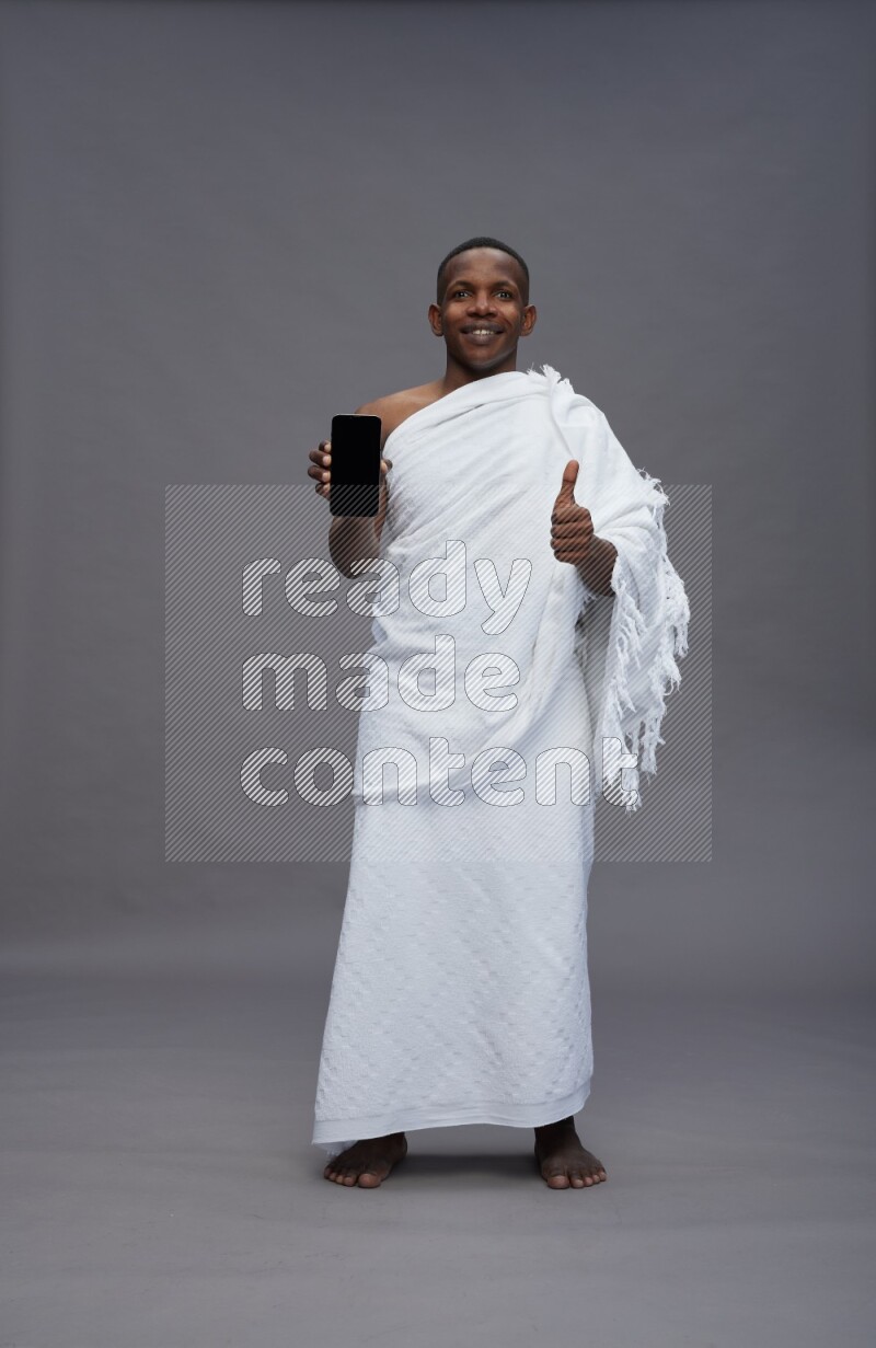 A man wearing Ehram Standing showing phone to camera on gray background