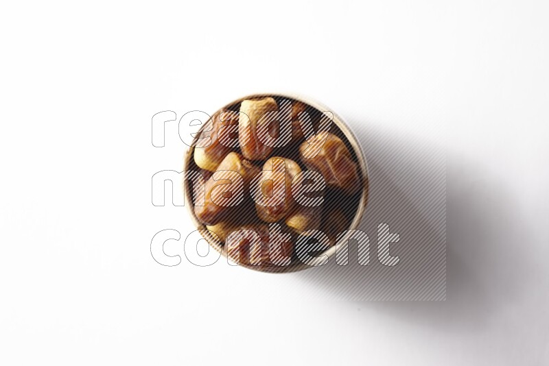 Dates in a beige pottery bowl on white background