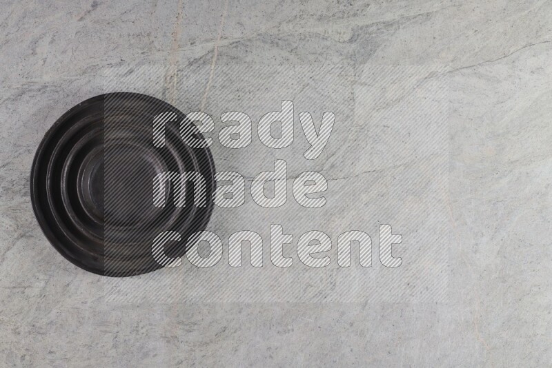 A pottery black ripple plate on grey marble background