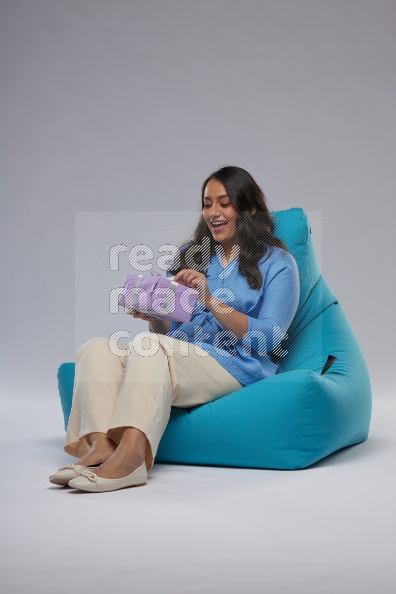 A woman sitting on a blue beanbag and holding a gift