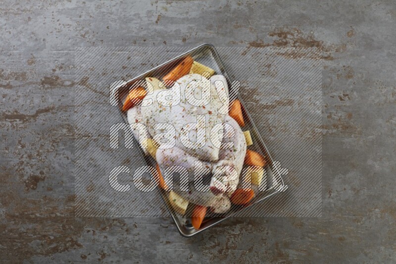 whole Raw chicken on a small oven trey direct on a rustic grey background