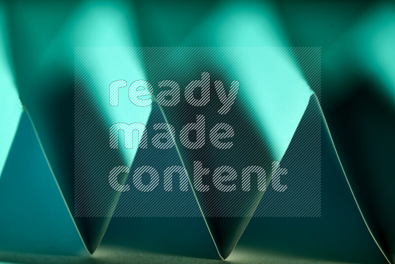 A close-up abstract image showing sharp geometric paper folds in green gradients