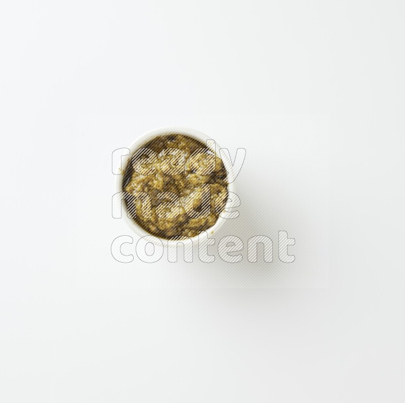 small white ceramic round bowl filled with pesto paste on a white counter top