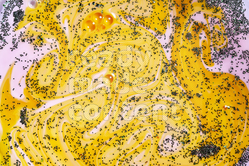 A close-up of sparkling green glitter scattered on swirling yellow and pink background