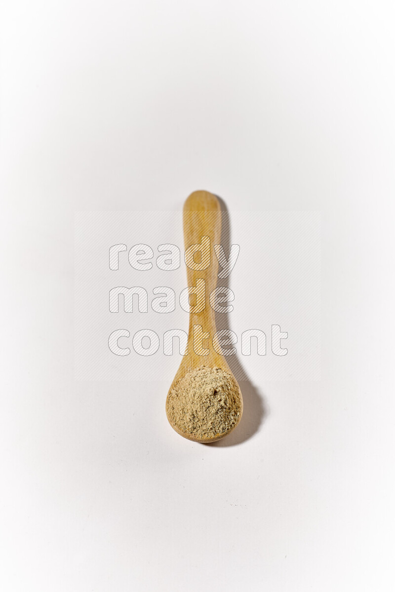 A wooden spoon full of ground ginger powder on white background