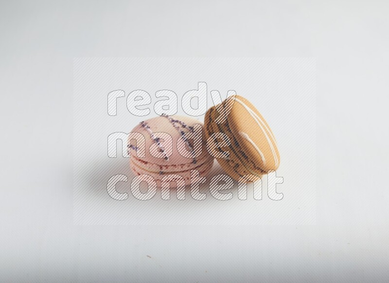 45º Shot of of two assorted Brown Irish Cream, and pink orange blossom macarons on white background