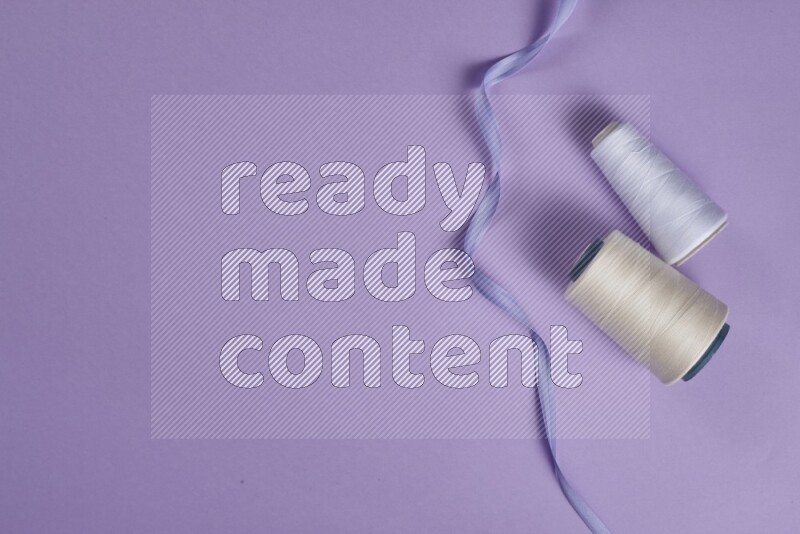 A white and purple collection of sewing and tailoring tools arranged on a purple background