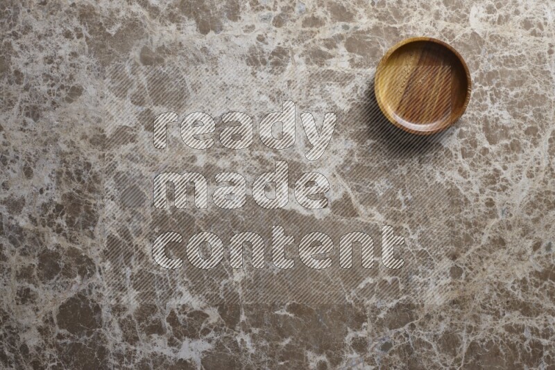 A wooden bowl on beige marble background