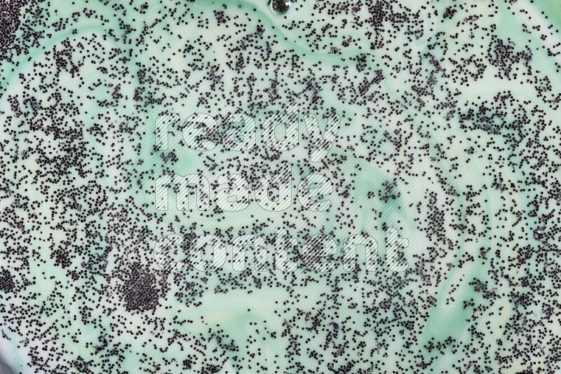 A close-up of sparkling purple glitter scattered on swirling green and white background
