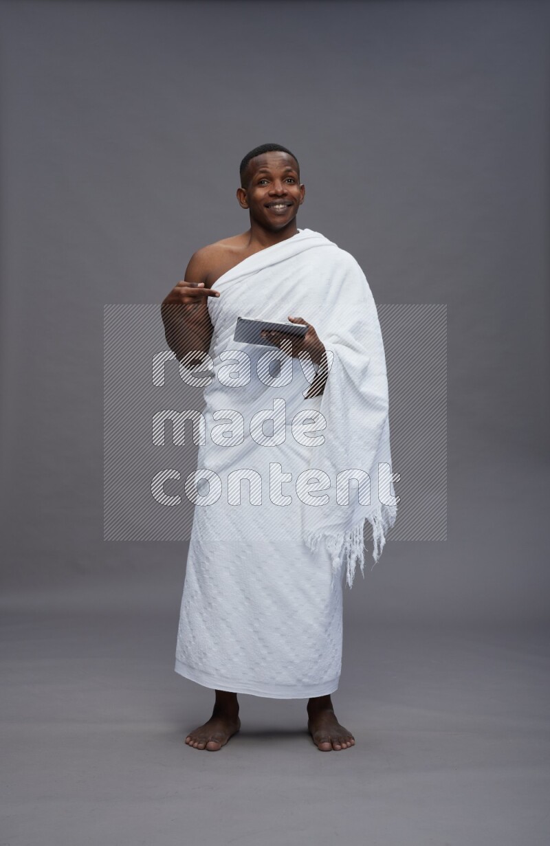 A man wearing Ehram Standing working on tablet on gray background