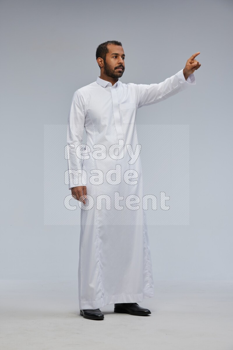 Saudi man Wearing Thob standing interacting with the camera on Gray background