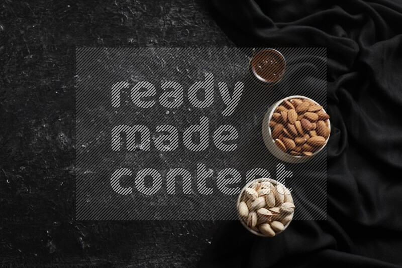 Nuts in pottery bowls with coffee in a dark setup