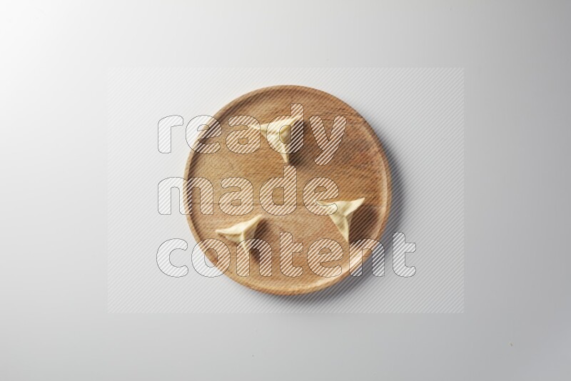 Three Sambosas on a wooden round plate on a white background