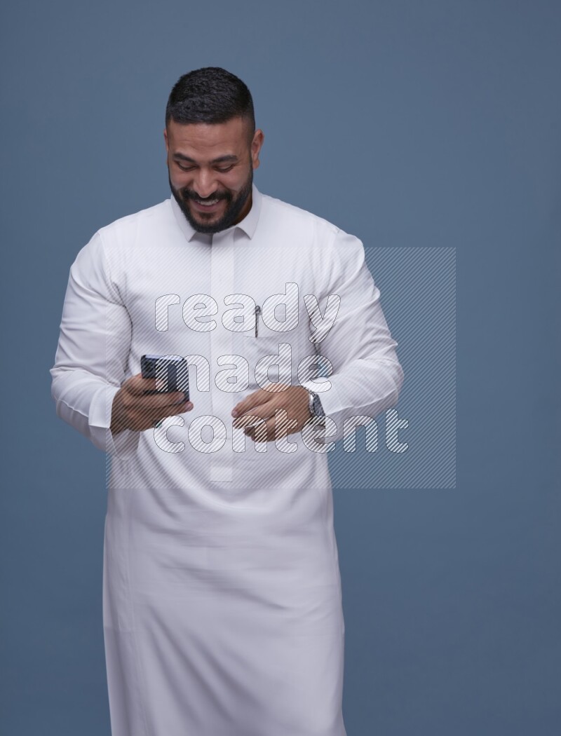 A man Texting on Blue Background wearing Saudi Thob