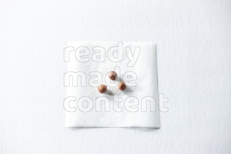 3 peeled hazelnuts on a piece of paper on a white background in different angles