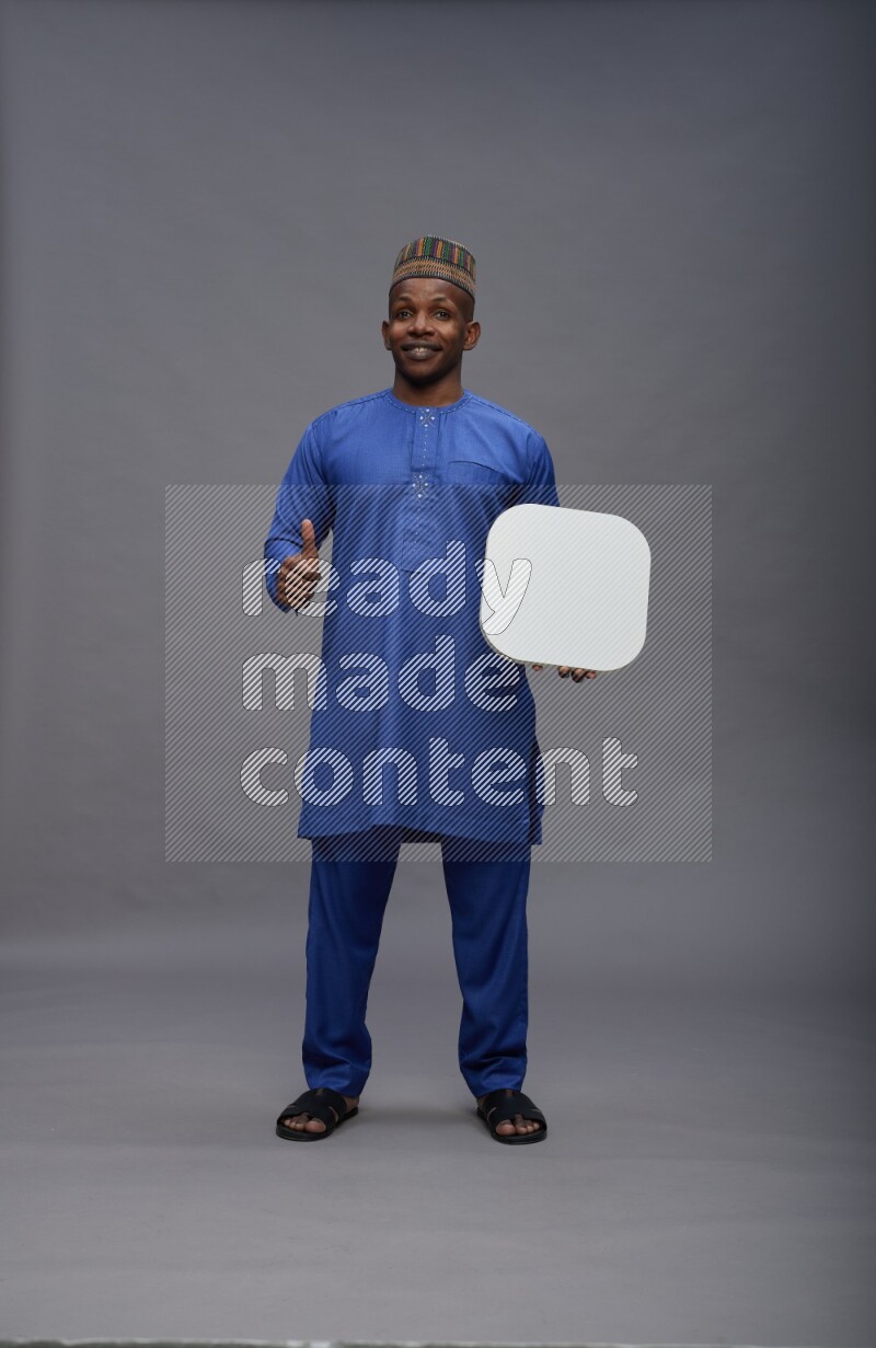 Man wearing Nigerian outfit standing holding social media sign on gray background