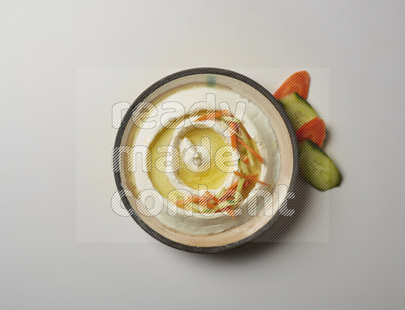 Lebnah garnished with sliced carrots &cucumber in a pottery plate on a white background