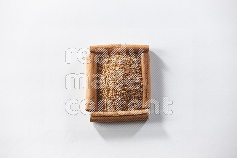 A single square of cinnamon sticks full of mustard seeds on white flooring