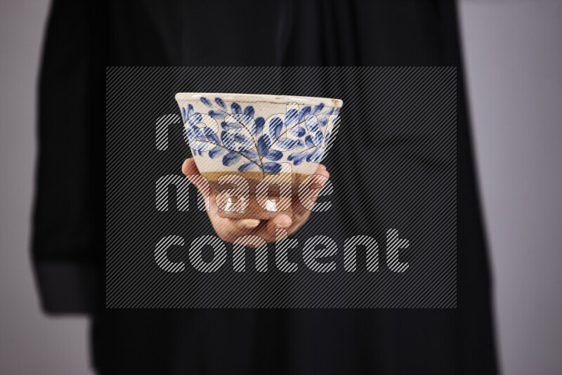A woman in black abaya holding different pottery essentials in different positions