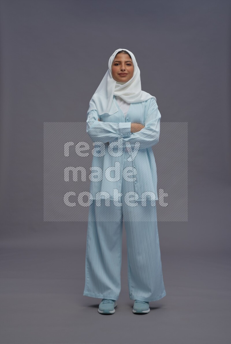 Saudi woman wearing hijab clothes standing with crossed arms on gray background