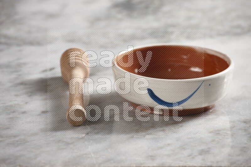Multicolored pottery bowl with wooden honey dipper on the side on grey marble background