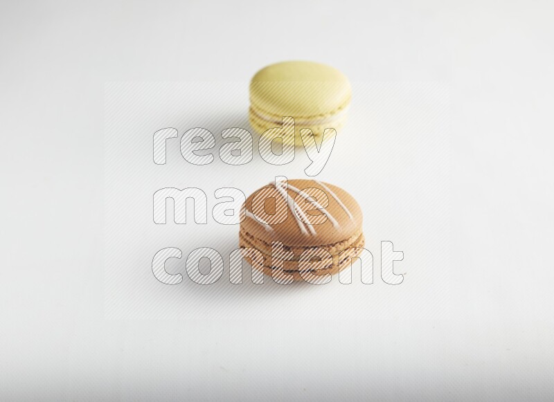 45º Shot of of two assorted Brown Irish Cream, and Yellow Lime macarons on white background