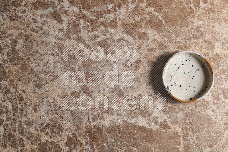 A multicolored pottery bowl on beige marble background