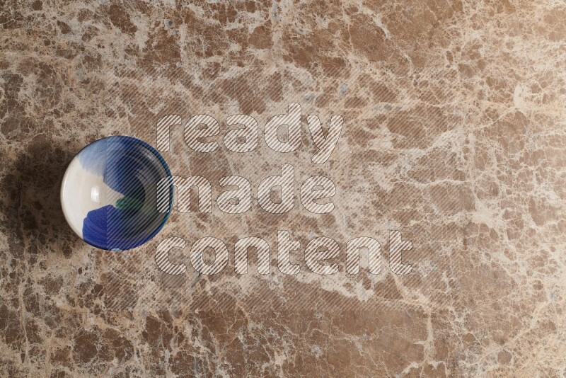 A multicolored pottery bowl on beige marble background
