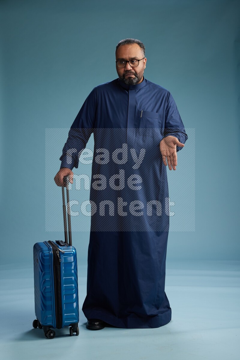 Saudi Man without shimag Standing pulling travel bag on blue background