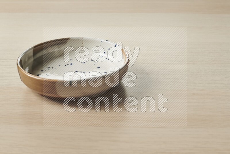 A multicolored pottery bowl on light wooden background
