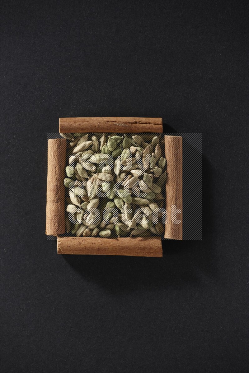 A single square of cinnamon sticks full of Cardamom on black flooring
